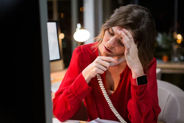 Напружена бізнес-леді розмовляє по телефону за столом — стокове фото