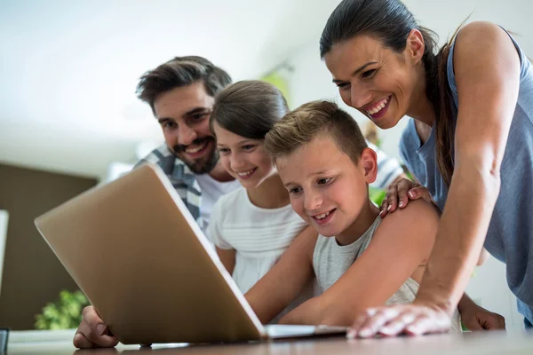 Família feliz usando laptop na sala de estar — Fotografia de Stock