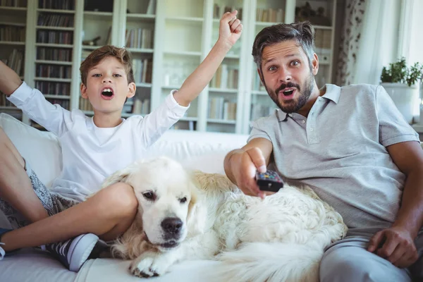 Padre e hijo sentados en sofá con perro mascota —  Fotos de Stock