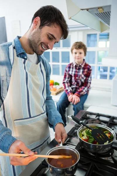 Menino olhando enquanto o pai cozinhar comida — Fotografia de Stock