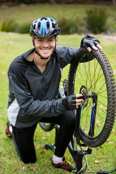 Ciclista masculino reparando sua bicicleta de montanha — Fotografia de Stock