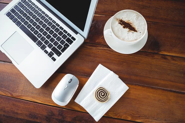 Filiżanka kawy i laptop na stole — Zdjęcie stockowe