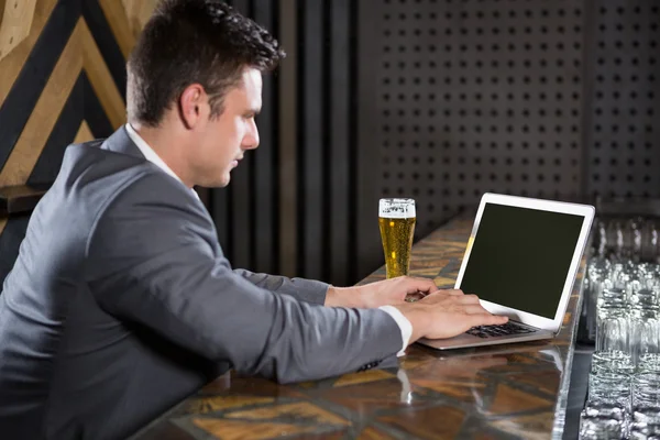 Homem usando laptop no balcão de bar — Fotografia de Stock