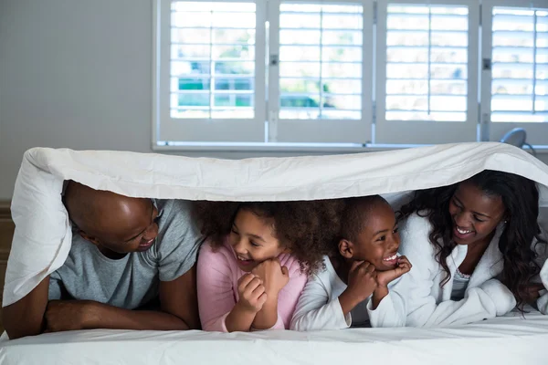 Familie liegt unter Decke auf Bett — Stockfoto