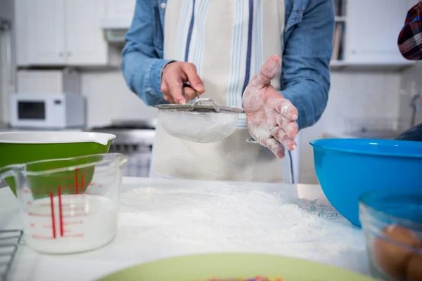 Man sifting flour through a sieve — Stock Photo, Image