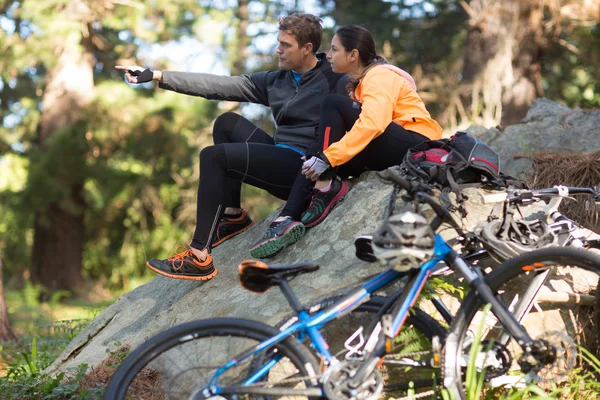 Biker paar zitten op rots wijzend op afstand — Stockfoto