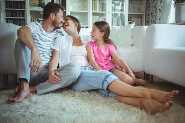 Familie zittend op tapijt in de woonkamer — Stockfoto