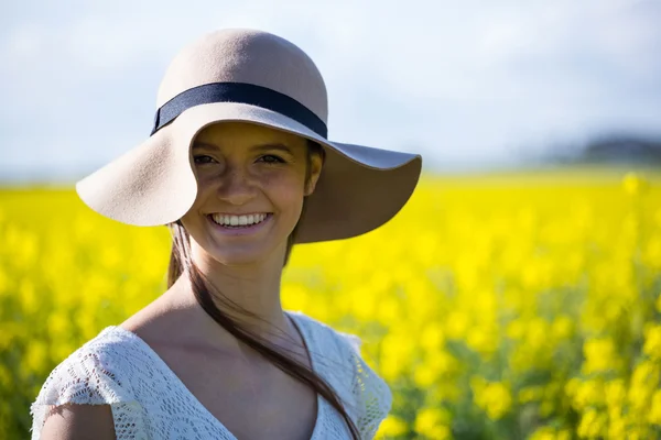 Kvinnan bär hatt och står i senap fält — Stockfoto