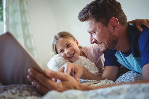 Vader liggend met dochter met behulp van Tablet PC — Stockfoto