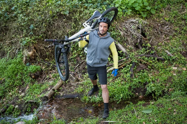 Motociclista de montanha masculino transportando bicicleta — Fotografia de Stock