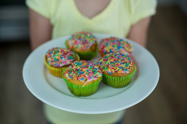 Mellersta delen av flicka håller plattan av cupcakes — Stockfoto