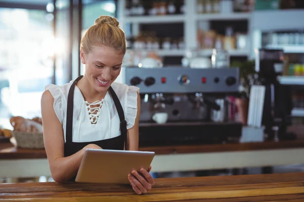 Waitress standing at counter using tablet — Stock Photo, Image