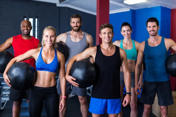 Amici che tengono palla esercizio in palestra — Foto Stock