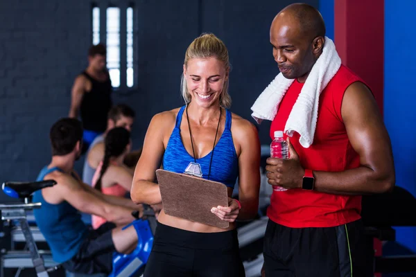 Fitness instructor discussing with man in gym — Stock Photo, Image