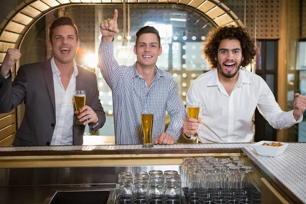 Friends raising their fist while having beer — Stock Photo, Image