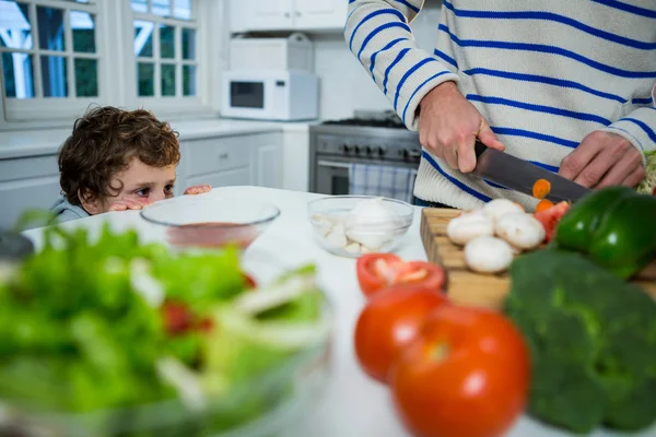 Chico mirando mientras padre cortar verduras —  Fotos de Stock