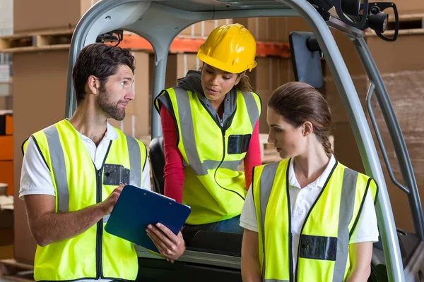 Magazijn werknemers praten met heftruck chauffeur — Stockfoto