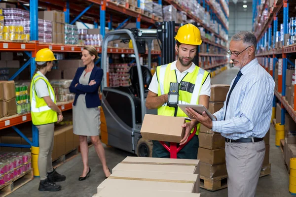 Warehouse manager holding tablet while worker — Stock Photo, Image