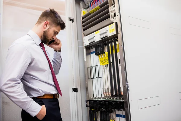 Technician talking on mobile phone in server room — Stock Photo, Image