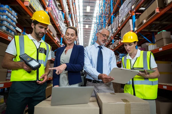 Warehouse manager and client interacting with co-workers — Stockfoto