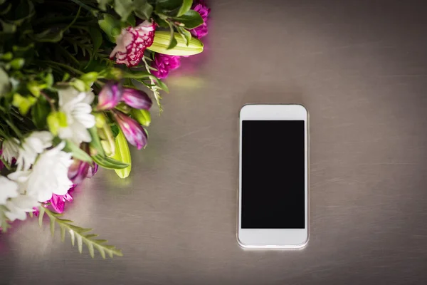 Flores y teléfono móvil en la mesa —  Fotos de Stock