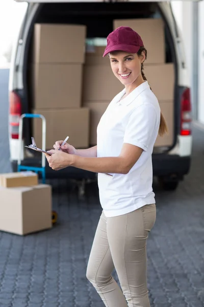 Delivery woman holding clipboard — Stockfoto