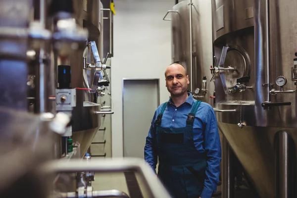 Owner standing amidst manufacturing equipment — ストック写真