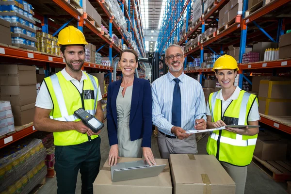 Warehouse manager and client standing with co-workers — Stockfoto