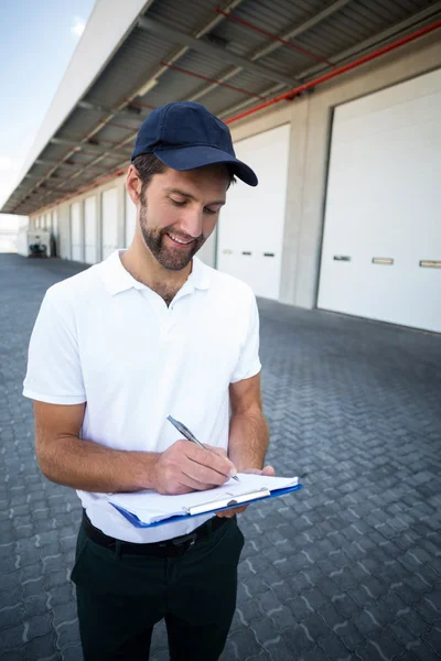 Entrega hombre escribiendo en portapapeles — Foto de Stock