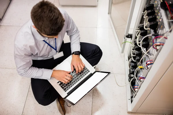 Técnico usando laptop ao analisar o servidor — Fotografia de Stock