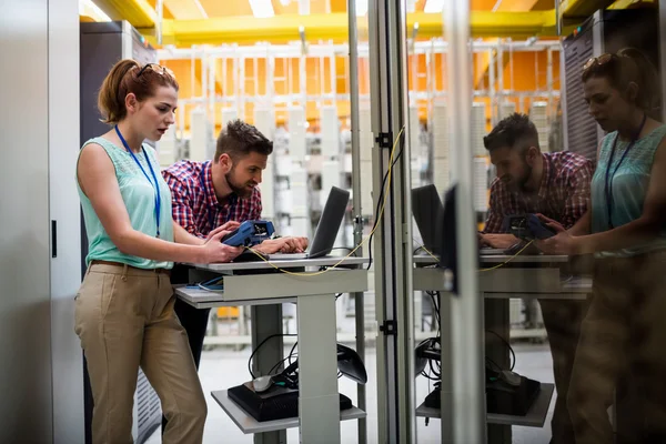 Technicians using laptop while analyzing server — Stock fotografie