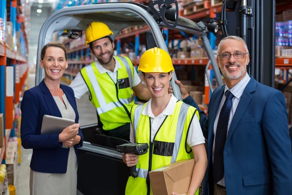 Warehouse manager and client standing with co-workers — Stockfoto