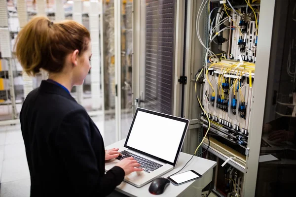Technician using laptop while analyzing server — Stock fotografie