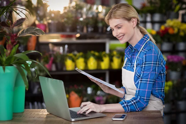 Florist using laptop while holding clipboard — Φωτογραφία Αρχείου
