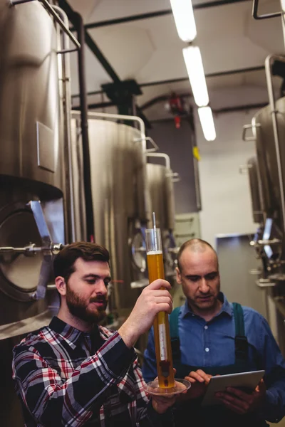 Travailleur et propriétaire inspectant la bière à la brasserie — Photo