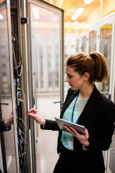 Tecnico che tiene tablet durante l'esame del server — Foto Stock