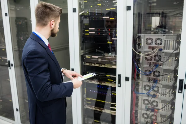Technician holding clipboard while analyzing server — Stock fotografie