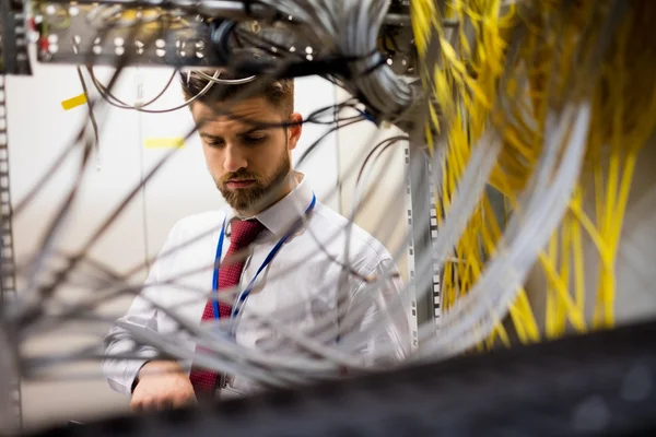 Técnico verificando cabos em um servidor montado em rack — Fotografia de Stock