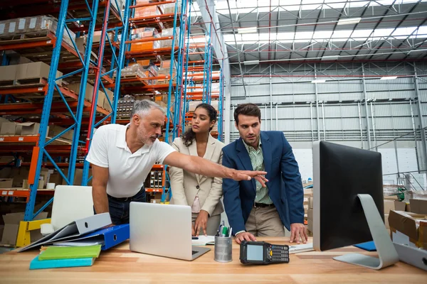 Warehouse managers and worker discussing with computer — Stockfoto
