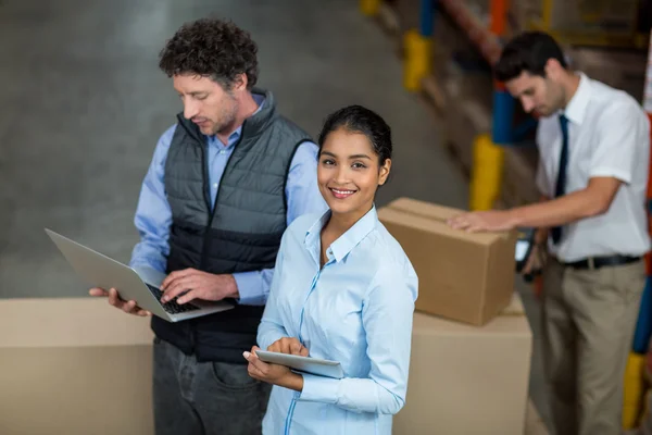 Warehouse workers using laptop and digital tablet — Stock Photo, Image