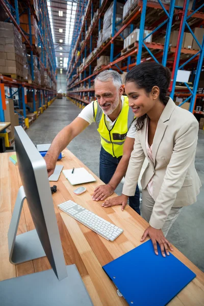 Warehouse manager and worker discussing with computer — Stockfoto