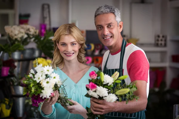 Floristas segurando monte de flores na loja — Fotografia de Stock