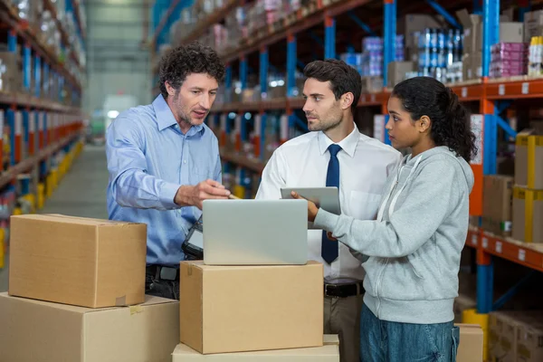 Gerente de almacén y trabajadores discutiendo con el ordenador portátil — Foto de Stock