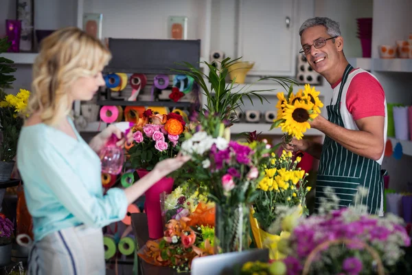 Blumenhändler sprüht Wasser auf Blumen im Geschäft — Stockfoto
