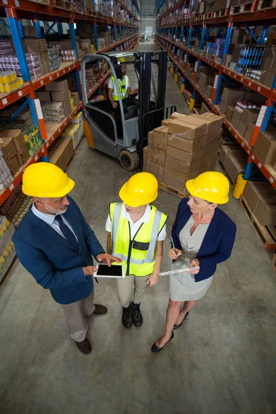 Gerente de armazém usando tablet com cliente e trabalhador — Fotografia de Stock