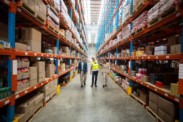 Warehouse team discussing while walking — Stockfoto