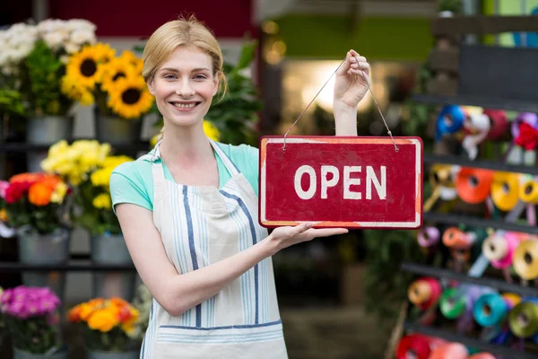 Vrouwelijke bloemist bedrijf open uithangbord — Stockfoto