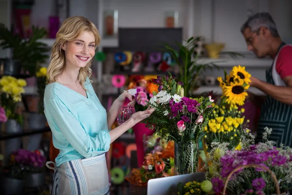 Fiorista spruzzando acqua su fiori in negozio — Foto Stock