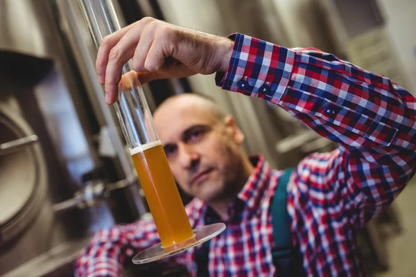 Proprietário examinando cerveja em tubo de vidro — Fotografia de Stock