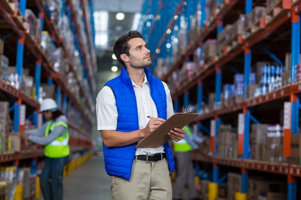 Trabajador de almacén escribiendo en portapapeles — Foto de Stock